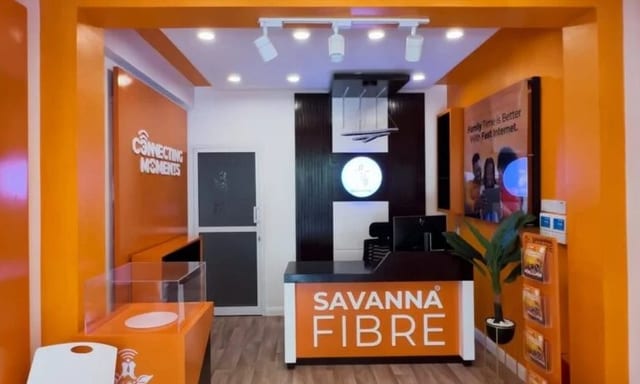 Reception area inside a Savanna Fibre office, with an orange branded desk and walls.