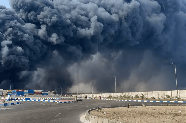 An image showing a massive fireball rises into the night sky following the devastating explosion at Iran’s Bandar Abbas Port, with thick...